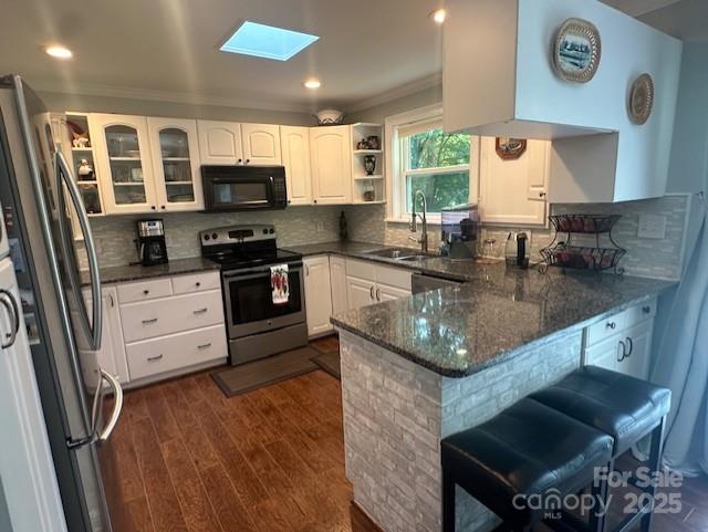 3211 Winding Trl, Matthews, NC 28105 - kitchen with stainless steel appliances, a peninsula, a skylight, white cabinetry, and open shelves