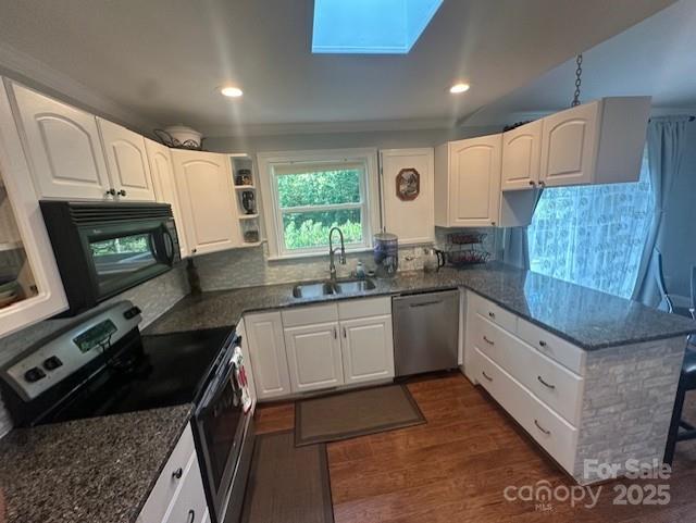 3211 Winding Trl, Matthews, NC 28105 - kitchen with appliances with stainless steel finishes, a skylight, dark stone counters, a peninsula, and dark wood-style flooring