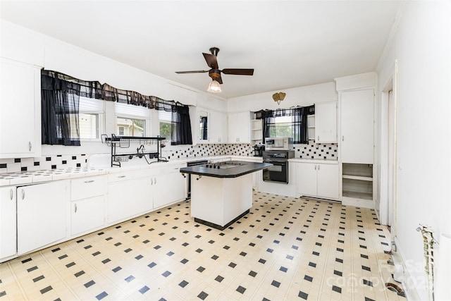 135 Corban Ave SE, Concord, NC 28025 - kitchen with black oven, backsplash, white cabinets, a ceiling fan, and stainless steel microwave