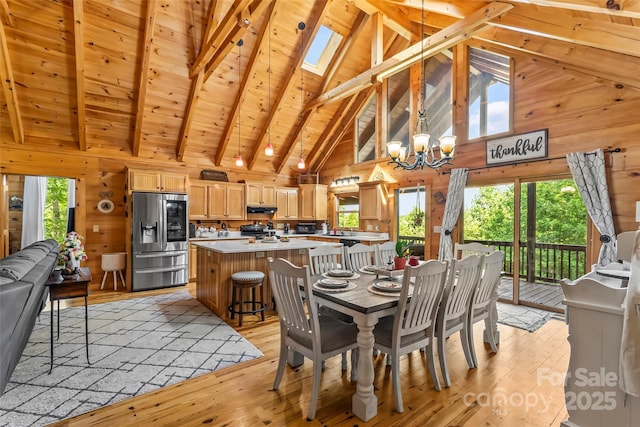 279 Outback Trl, Nebo, NC 28761 - dining space featuring wooden walls, light wood-type flooring, a chandelier, high vaulted ceiling, and a skylight