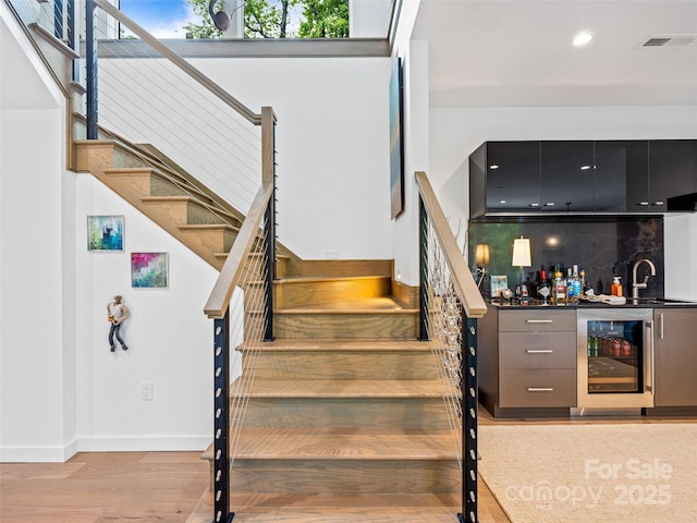 23 Haverhill Ct, Flat Rock, NC 28731 - stairway featuring wine cooler, bar with sink, wood finished floors, and recessed lighting