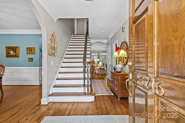 6716 Southby Ct, Charlotte, NC 28270 - entrance foyer with arched walkways, wood finished floors, stairs, crown molding, and a wainscoted wall