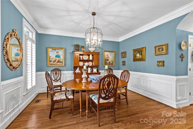 6716 Southby Ct, Charlotte, NC 28270 - dining area featuring a chandelier, wood finished floors, ornamental molding, arched walkways, and a wainscoted wall