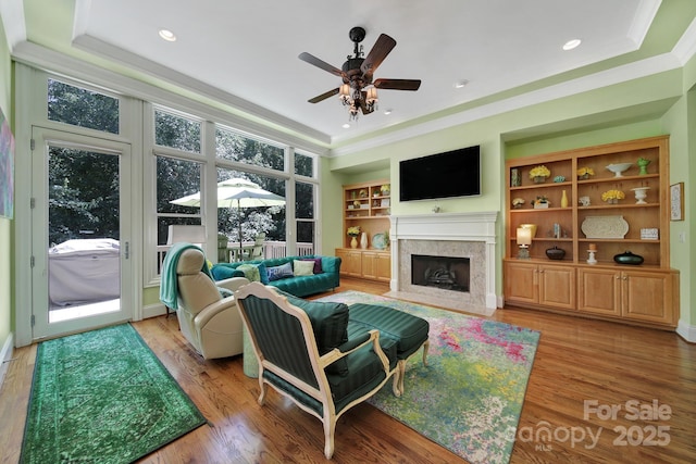 166 Atlantic Way, Mooresville, NC 28117 - living area featuring crown molding, a premium fireplace, a ceiling fan, a tray ceiling, and light wood-style floors