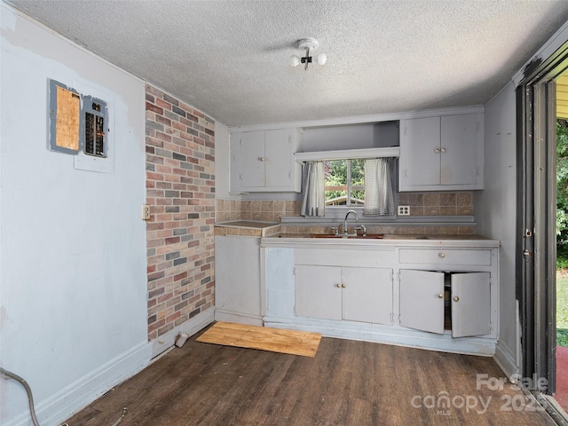 51 Riverbend St, Waynesville, NC 28786 - kitchen with a textured ceiling, dark wood-type flooring, brick wall, decorative backsplash, and white cabinetry
