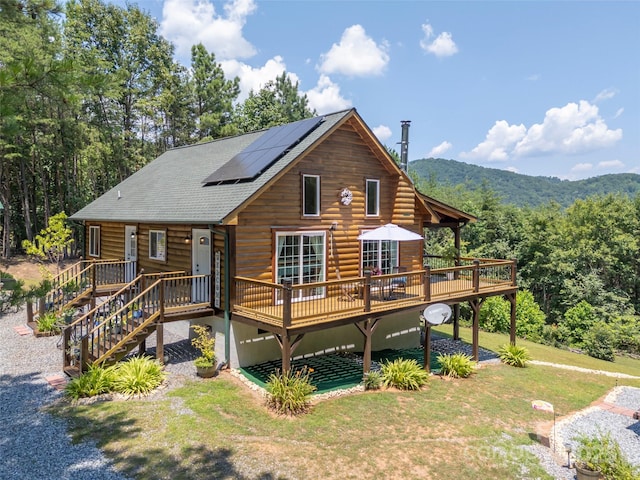 334 Arbra Mountain Way, Bostic, NC 28018 - rear view of house featuring a lawn, a deck with mountain view, roof mounted solar panels, and a shingled roof