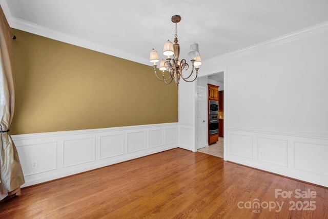 5138 Foxbriar Trl, Charlotte, NC 28269 - empty room with a chandelier, crown molding, a wainscoted wall, wood finished floors, and a decorative wall