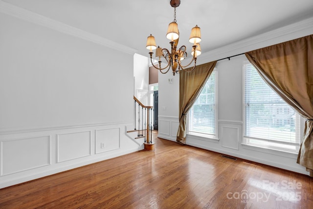 5138 Foxbriar Trl, Charlotte, NC 28269 - unfurnished dining area featuring a chandelier, plenty of natural light, stairway, wainscoting, and ornamental molding