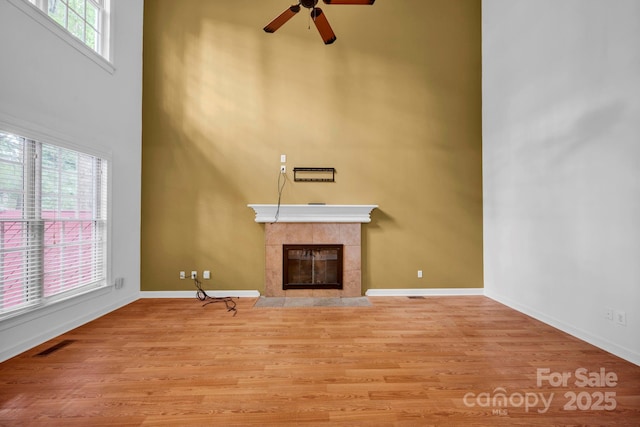 5138 Foxbriar Trl, Charlotte, NC 28269 - unfurnished living room with a high ceiling, a ceiling fan, a tile fireplace, and wood finished floors