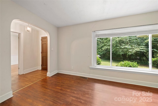 7010 Monroe Rd, Charlotte, NC 28212 - unfurnished room with arched walkways, wood finished floors, and healthy amount of natural light