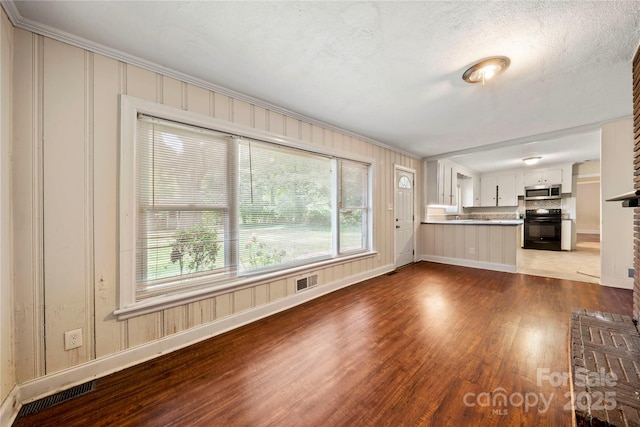 7010 Monroe Rd, Charlotte, NC 28212 - unfurnished living room featuring wood finished floors, crown molding, plenty of natural light, a textured ceiling, and a fireplace