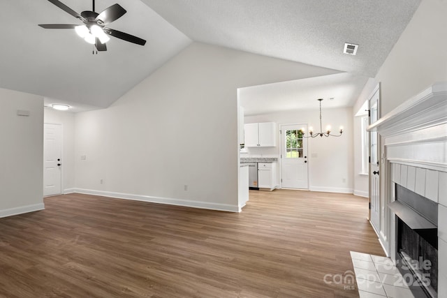 2210 Dawn Rdg, Monroe, NC 28110 - unfurnished living room with a chandelier, a fireplace, a ceiling fan, vaulted ceiling, and light wood-style floors