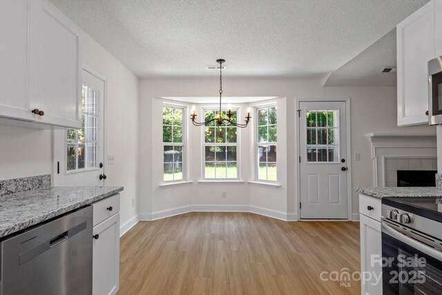 2210 Dawn Rdg, Monroe, NC 28110 - kitchen featuring appliances with stainless steel finishes, light wood-style flooring, a chandelier, white cabinetry, and a textured ceiling