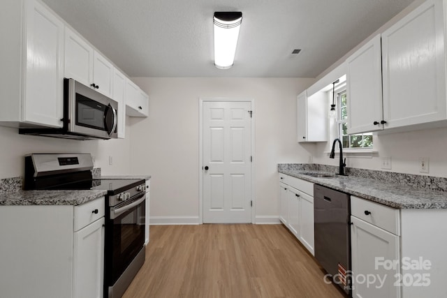 2210 Dawn Rdg, Monroe, NC 28110 - kitchen with appliances with stainless steel finishes, light wood-type flooring, light stone countertops, and white cabinets