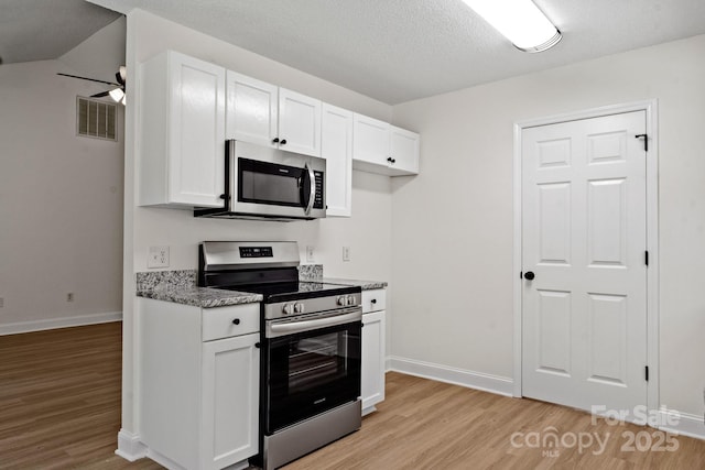 2210 Dawn Rdg, Monroe, NC 28110 - kitchen with appliances with stainless steel finishes, light wood finished floors, white cabinetry, a textured ceiling, and light stone counters
