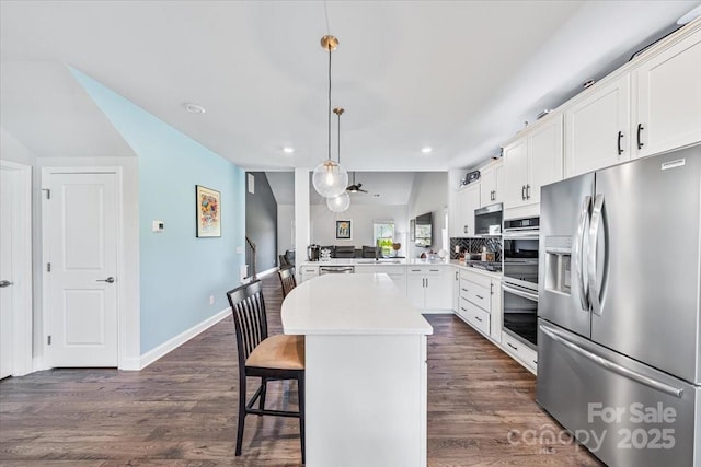 1302 Black Walnut St, Monroe, NC 28112 - kitchen with stainless steel appliances, a peninsula, a center island, vaulted ceiling, and dark wood-style floors