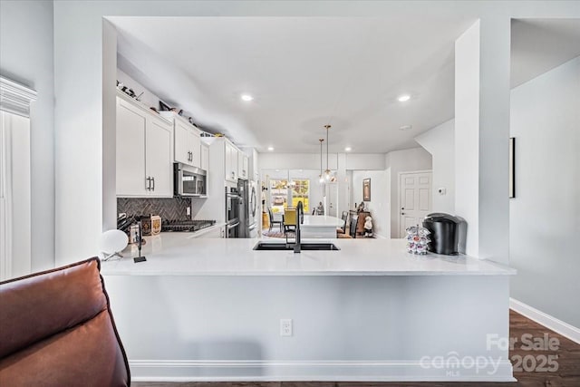 1302 Black Walnut St, Monroe, NC 28112 - kitchen featuring appliances with stainless steel finishes, a peninsula, recessed lighting, light countertops, and white cabinets