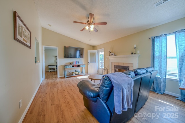 1975 8th Street Ln SE, Hickory, NC 28602 - living area with light wood-style flooring, ceiling fan, a tile fireplace, lofted ceiling, and a textured ceiling