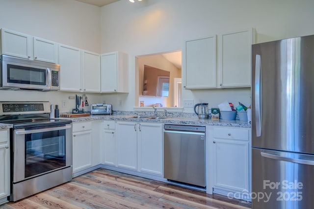 1975 8th Street Ln SE, Hickory, NC 28602 - kitchen with appliances with stainless steel finishes, light stone countertops, light wood-type flooring, and white cabinetry