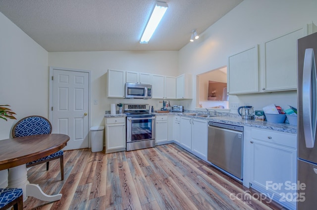 1975 8th Street Ln SE, Hickory, NC 28602 - kitchen featuring appliances with stainless steel finishes, white cabinets, a textured ceiling, light stone counters, and light wood finished floors