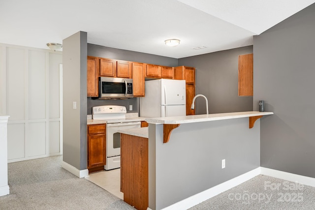 64 Foxden Dr Unit 201, Fletcher, NC 28732 - kitchen featuring white appliances, a breakfast bar, a peninsula, and brown cabinetry