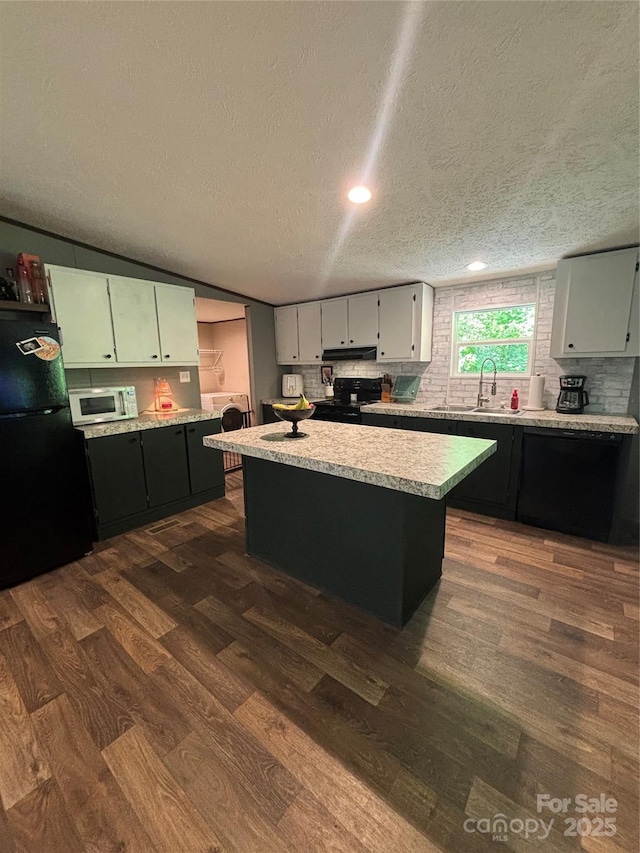 2877 Shannon St, Sharon, SC 29742 - kitchen with black appliances, under cabinet range hood, dark wood-style flooring, light countertops, and a kitchen island