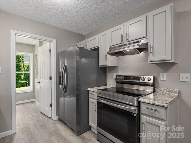 19 Cedar St, Canton, NC 28716 - kitchen with stainless steel appliances, under cabinet range hood, light wood-style flooring, a textured ceiling, and light stone countertops