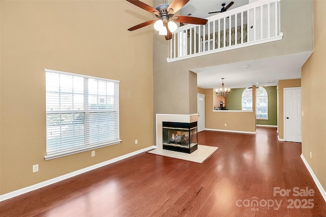 4580 Antelope Ln, Charlotte, NC 28269 - unfurnished living room featuring a towering ceiling, a ceiling fan, wood finished floors, a chandelier, and a multi sided fireplace