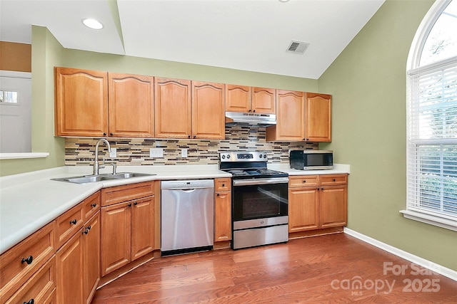 4580 Antelope Ln, Charlotte, NC 28269 - kitchen featuring stainless steel appliances, under cabinet range hood, backsplash, dark wood-style flooring, and light countertops