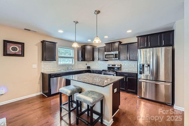10920 Dapple Grey Ln, Charlotte, NC 28213 - kitchen featuring stainless steel appliances, light stone countertops, wood finished floors, backsplash, and a kitchen island