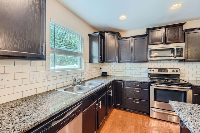 10920 Dapple Grey Ln, Charlotte, NC 28213 - kitchen with stainless steel appliances, light wood finished floors, backsplash, dark brown cabinets, and dark stone counters
