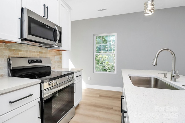 226 N Columbia Ave, Rock Hill, SC 29730 - kitchen with stainless steel appliances, backsplash, white cabinetry, light wood finished floors, and hanging light fixtures