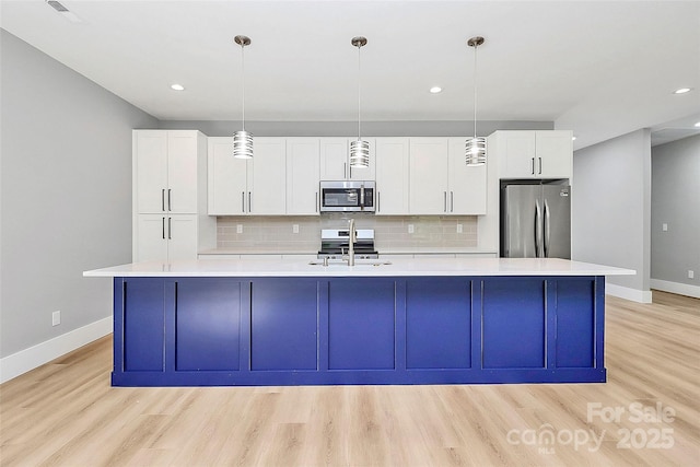 5516 Old York Rd, Rock Hill, SC 29732 - kitchen featuring appliances with stainless steel finishes, a large island with sink, light countertops, light wood-style floors, and white cabinets