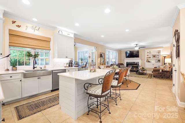 15933 Glen Miro Dr, Huntersville, NC 28078 - kitchen with stainless steel dishwasher, ceiling fan, a kitchen bar, a glass covered fireplace, and backsplash