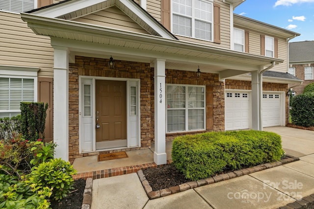 1504 Jekyll Ln, Waxhaw, NC 28173 - doorway to property featuring concrete driveway, an attached garage, stone siding, and covered porch