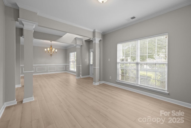 1504 Jekyll Ln, Waxhaw, NC 28173 - unfurnished living room with decorative columns, a chandelier, light wood-style floors, and ornamental molding