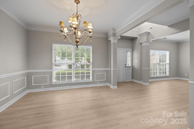 1504 Jekyll Ln, Waxhaw, NC 28173 - spare room featuring decorative columns, a chandelier, light wood-style floors, ornamental molding, and a wainscoted wall