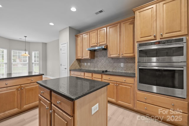 1504 Jekyll Ln, Waxhaw, NC 28173 - kitchen with stainless steel double oven, under cabinet range hood, a kitchen island, tasteful backsplash, and light wood-type flooring