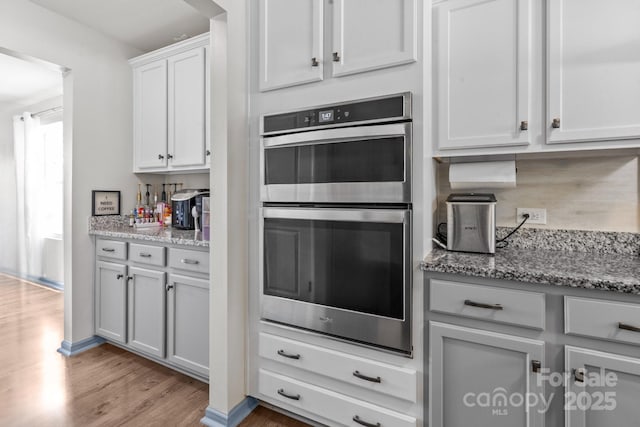 712 Coventry Dr, Albemarle, NC 28001 - kitchen featuring stainless steel double oven, light wood-style floors, light stone countertops, and white cabinetry