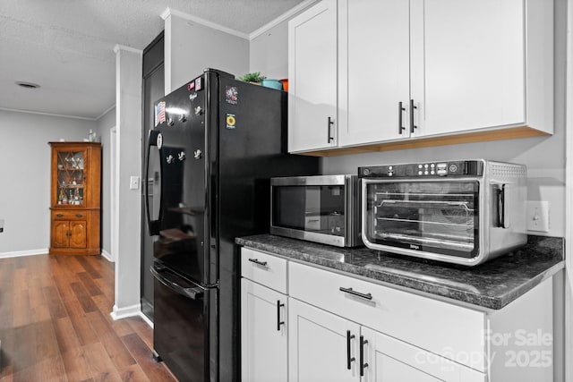 1560 Lafayette Ave, Hudson, NC 28638 - kitchen featuring stainless steel microwave, ornamental molding, dark wood finished floors, white cabinets, and freestanding refrigerator