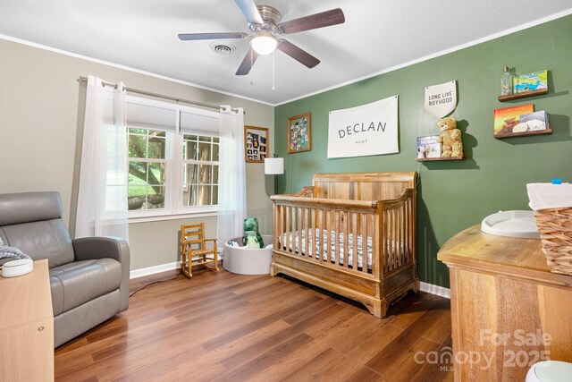 1560 Lafayette Ave, Hudson, NC 28638 - bedroom with a crib, wood finished floors, crown molding, and ceiling fan