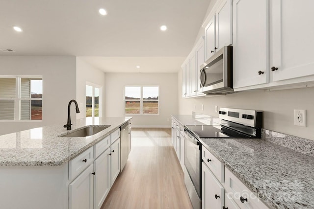 1066 Russell Dr, Winston Salem, NC 27127 - kitchen with stainless steel appliances, light wood-style flooring, recessed lighting, white cabinets, and an island with sink