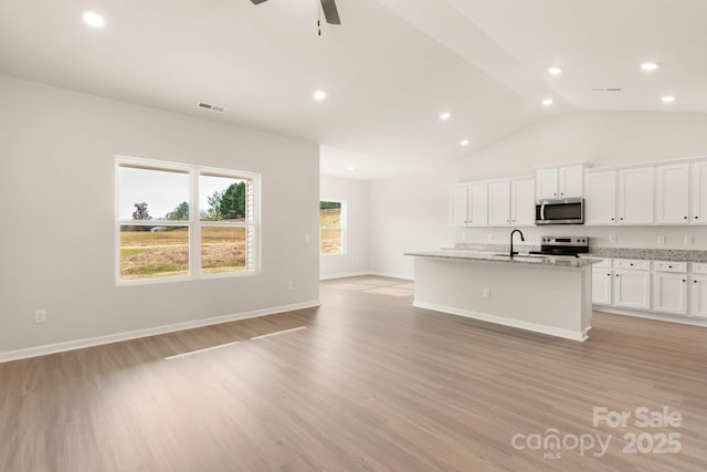 1066 Russell Dr, Winston Salem, NC 27127 - kitchen featuring appliances with stainless steel finishes, ceiling fan, a center island with sink, light wood finished floors, and vaulted ceiling