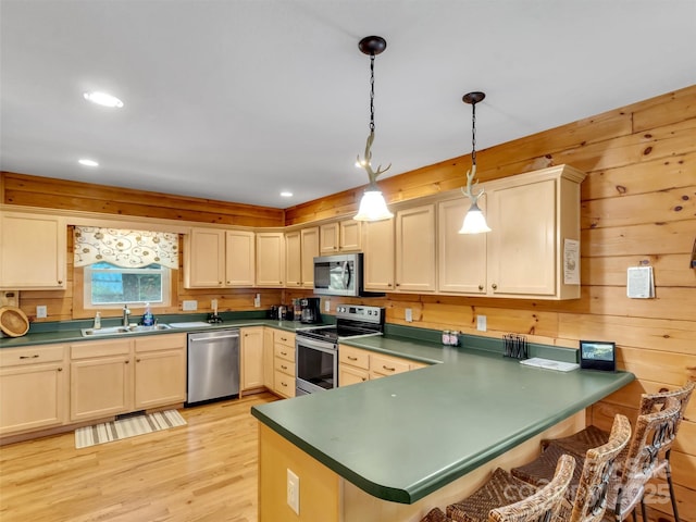 1064 Point Of View Dr, Waynesville, NC 28785 - kitchen featuring appliances with stainless steel finishes, dark countertops, a peninsula, pendant lighting, and light wood-style flooring