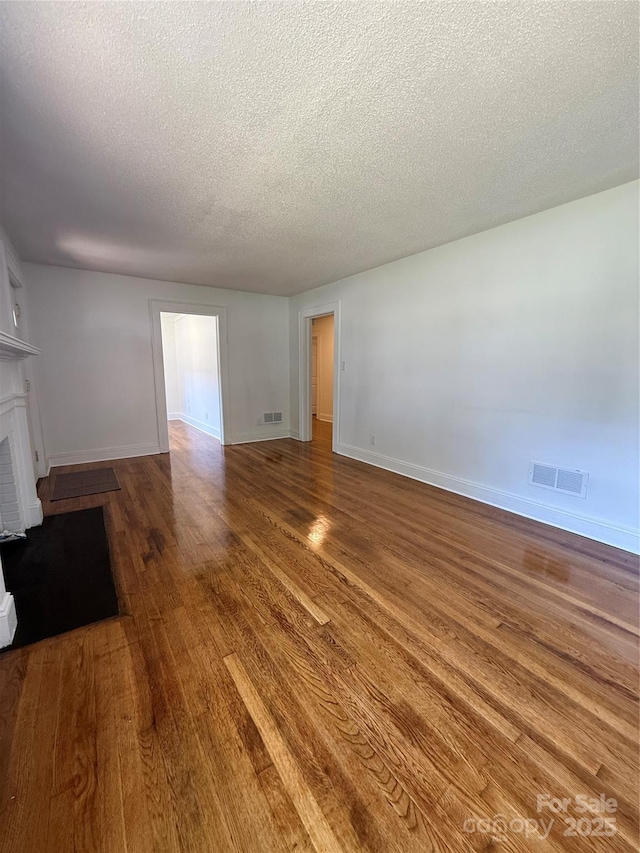 727 3rd Ave NW, Hickory, NC 28601 - unfurnished living room featuring wood finished floors, a textured ceiling, and a fireplace