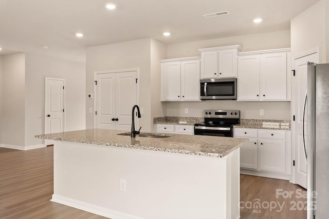 1070 Jonestown Rd, Winston Salem, NC 27127 - kitchen with stainless steel appliances, wood finished floors, white cabinetry, light stone counters, and recessed lighting