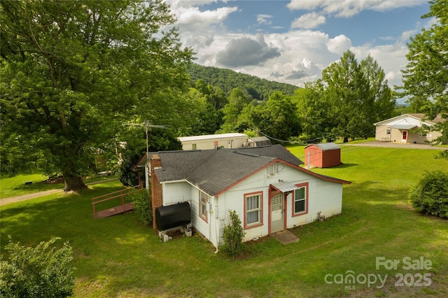 153 Beaverdam Loop Rd, Candler, NC 28715 - view of property exterior with a shingled roof, heating fuel, a lawn, an outdoor structure, and a wooded view