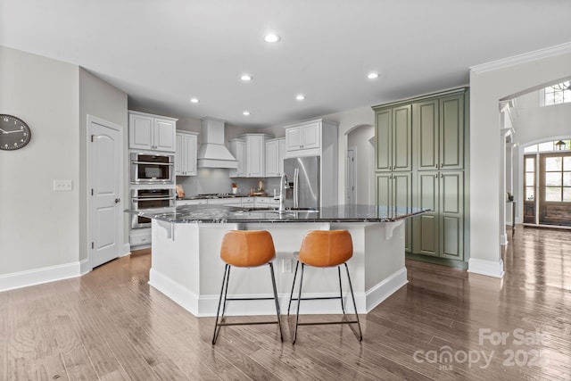 805 Hidden Pond Ln, Waxhaw, NC 28173 - kitchen with arched walkways, premium range hood, light wood-style flooring, a breakfast bar, and recessed lighting