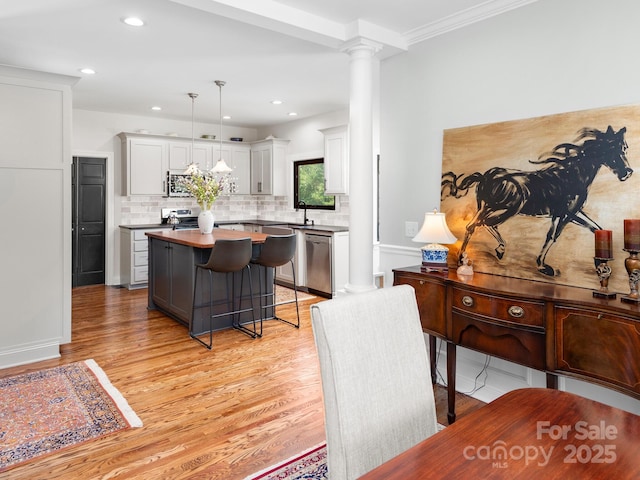 724 Moore Rd, Tryon, NC 28782 - kitchen featuring ornate columns, appliances with stainless steel finishes, a kitchen island, light wood-style flooring, and tasteful backsplash