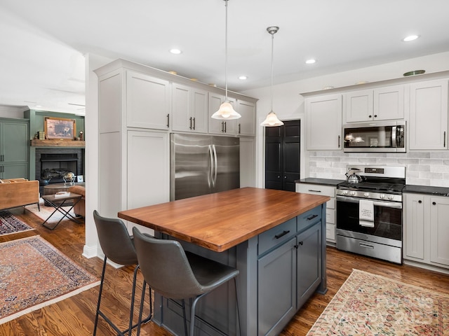 724 Moore Rd, Tryon, NC 28782 - kitchen featuring appliances with stainless steel finishes, wooden counters, backsplash, dark wood-type flooring, and a breakfast bar area